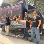 Grupo de activistas con pancarta frente a la fachada de un supermercado Vivanda en inauguración junto a un camión con pantalla publicitaria.